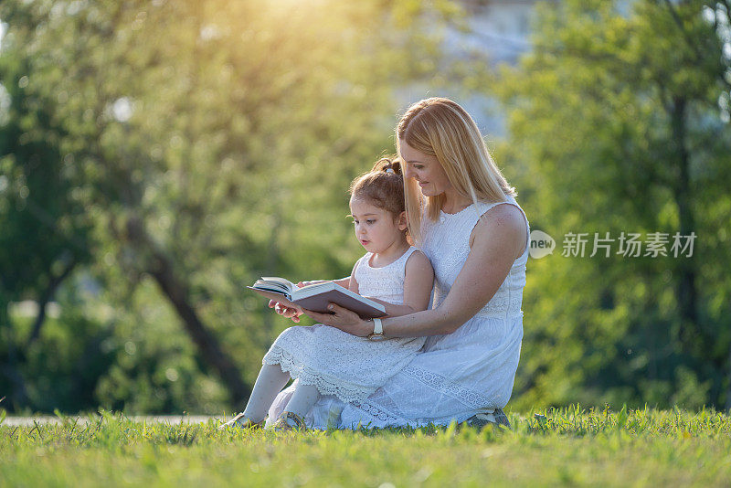母亲和女儿分享美好的时光与书在一个金色的下午
