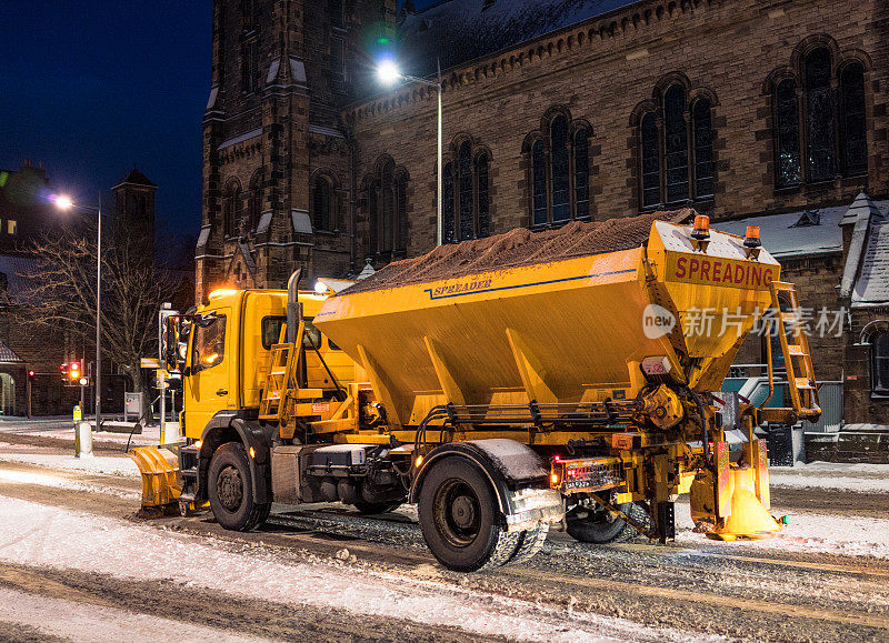 扫雪机清理道路和撒盐在晚上在英国城市