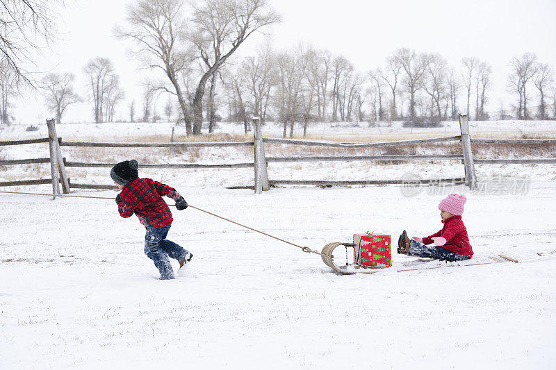 一个男孩拉着他蹒跚学步的妹妹在多巴哥的雪地上