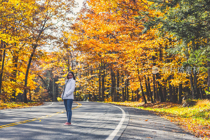 幸福的女人在秋叶飘落的路中间