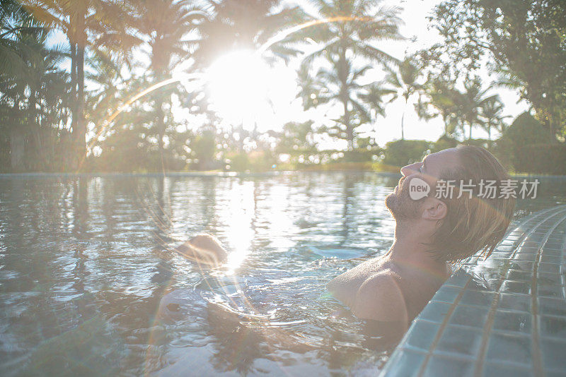 在度假村温泉的热水浴缸健康在热带天堂-男人放松在豪华度假村温泉撤退室外的热水浴缸池。快乐的年轻男模特放松休息在水上度假旅游。