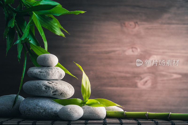 白色禅宗平衡石头和竹植物在木桌上
