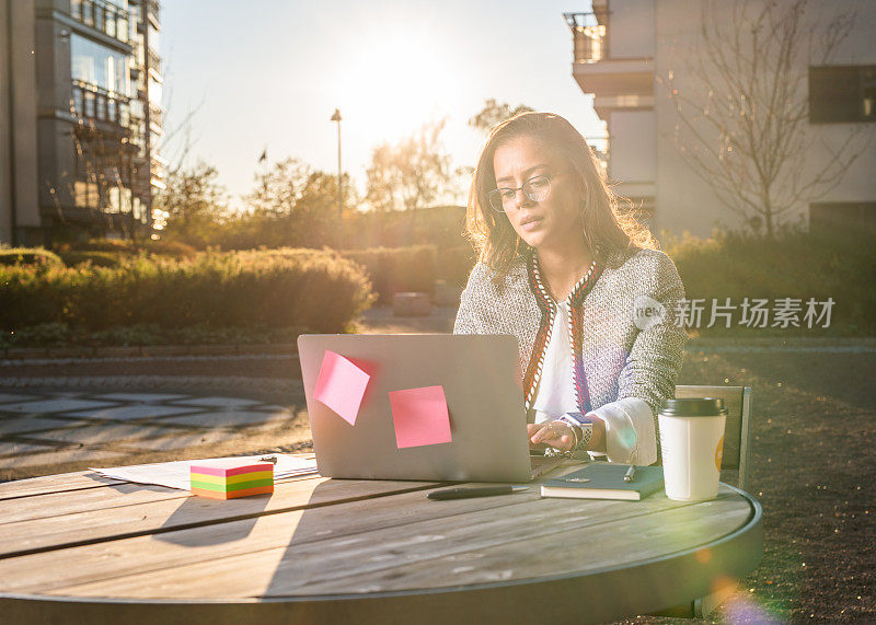 商务女性在户外使用笔记本电脑。