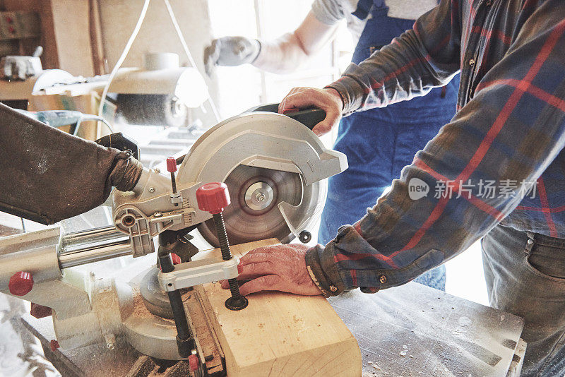 穿着工作服的师傅在锯木厂使用研磨机。