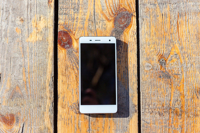 木质桌子上放着白色的智能手机