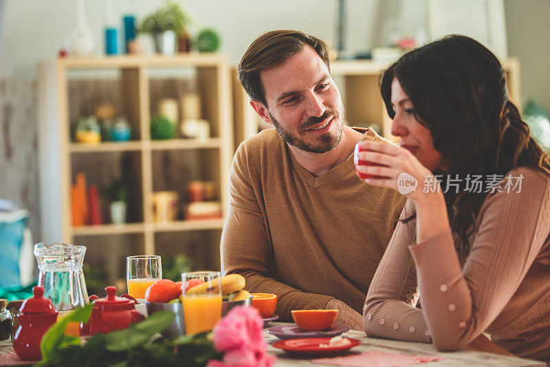 夫妻在家里吃早餐时聊天喝咖啡