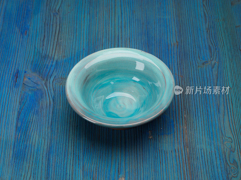 蓝色木桌上空的绿松石碗杯