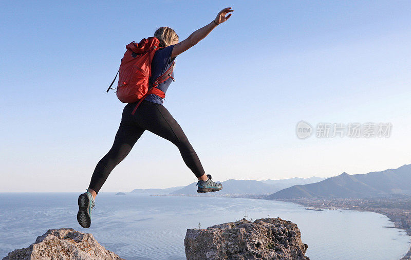 女性徒步旅行者在岩石峰顶之间跳跃
