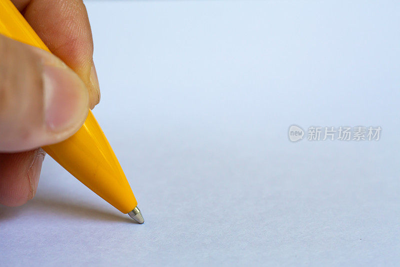 女人的左手拿着一支黄色的笔，在白纸背景上写信，笔记本，近距离微距拍摄，选择性聚焦，沟通，文具概念
