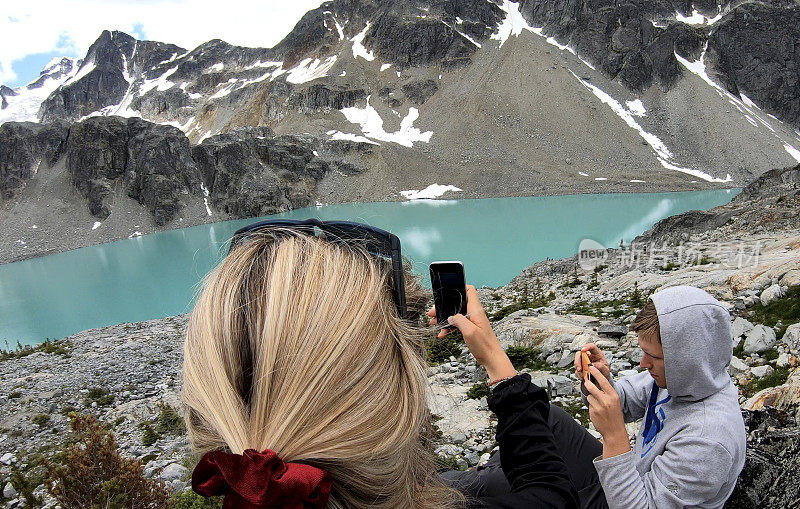 徒步者从山上的湖上方的巨石场拍照