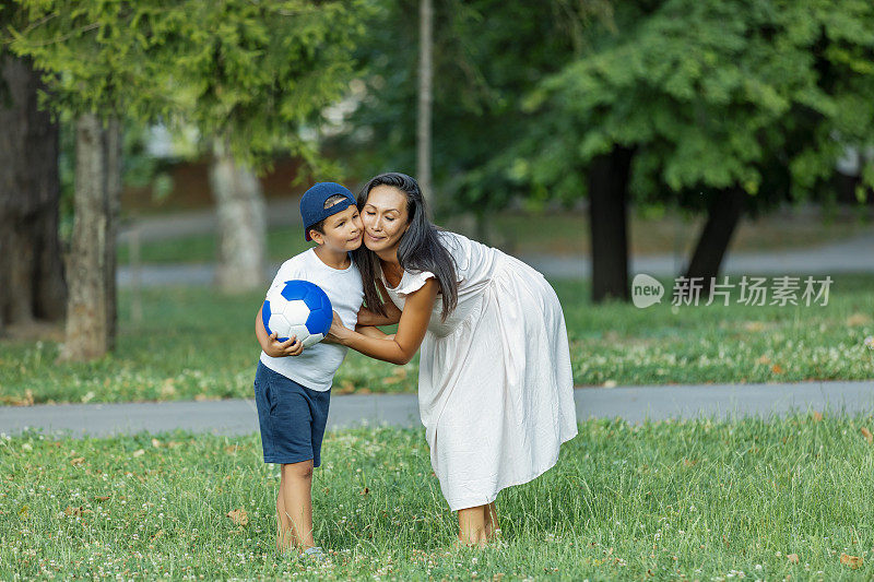 妈妈和儿子在公园里踢足球