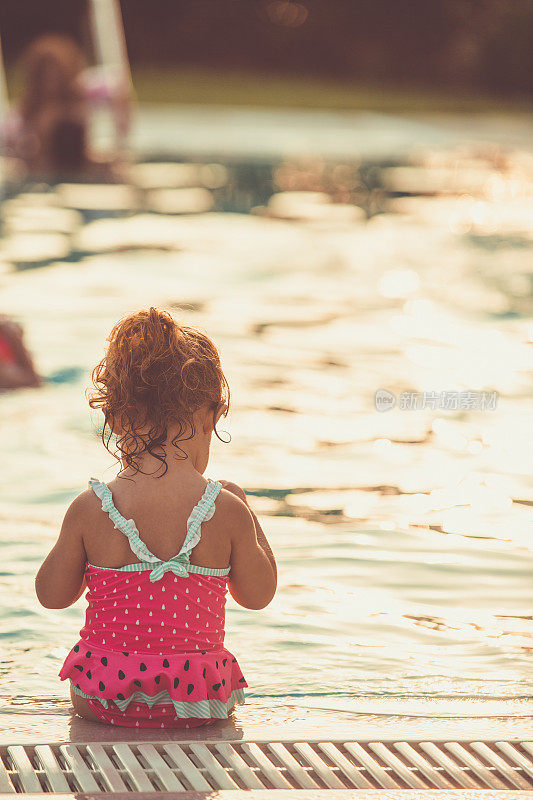 日落时分，小女孩坐在泳池边