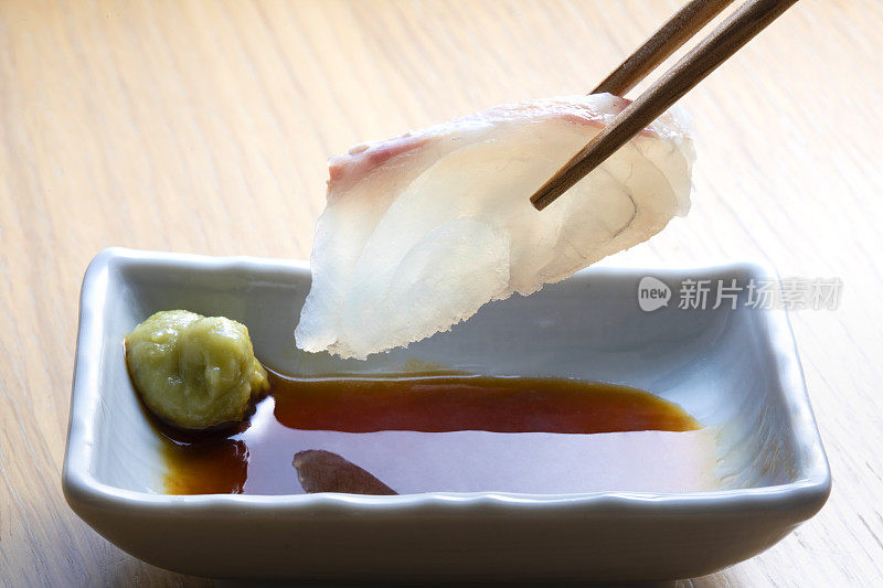 日本的生鱼片。用筷子夹住海鲷柳，加入酱油。