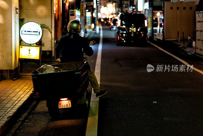 祗园，日本京都晚上与男人在大街上的摩托车送食物