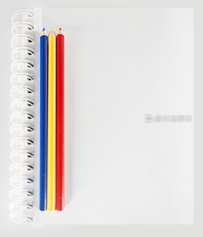 3支彩色铅笔在空白的白色素描纸上。在干净的白纸上复制空白。背景照片，用于艺术课或学校的信息、海报或签名。