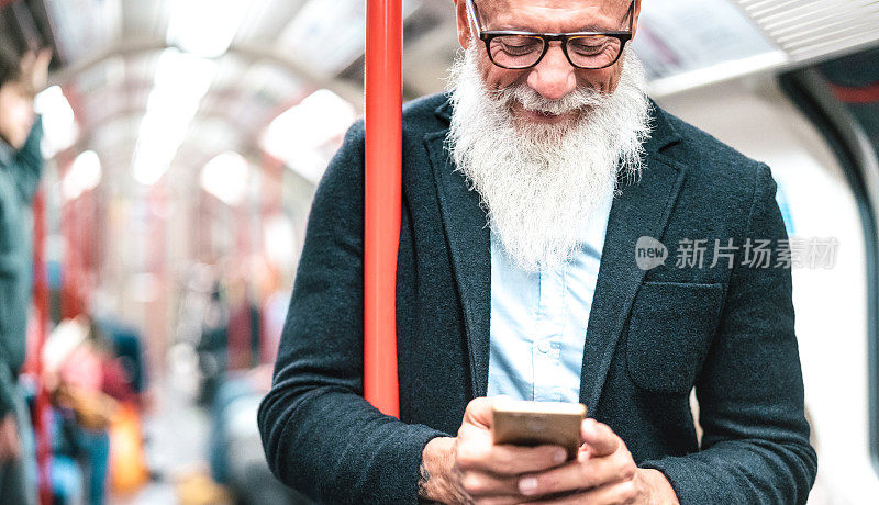 留着胡子的潮男在地铁里用手机玩手机-新潮的成年人用手机查看时刻表-快乐的生活方式和科技概念，没有年龄限制-室内霓虹过滤器