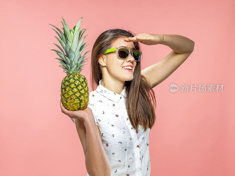 微笑的年轻女子与太阳镜拿菠萝在珊瑚的背景