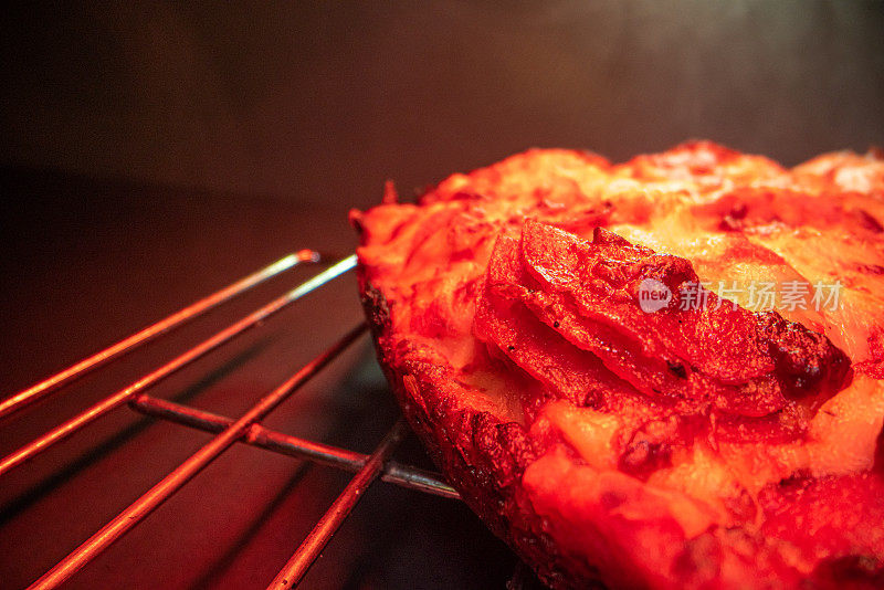 特写广角微距拍摄的美味热气腾腾的深盘皮辣香肠披萨新鲜出炉的烤箱在冷却架下的加热灯与复制空间