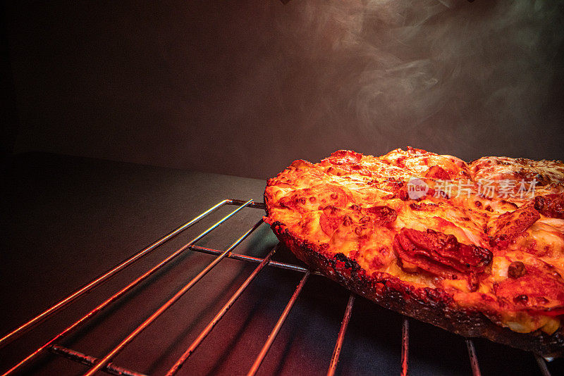 美味的热气腾腾的深盘辣香肠披萨新鲜出炉的烤箱在一个小冷却架下加热灯与复制空间