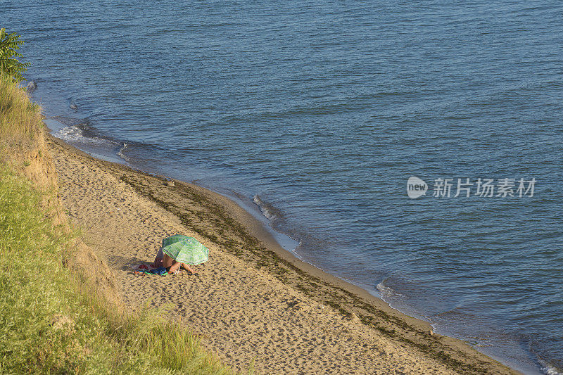 两个人在海边撑着伞晒太阳。