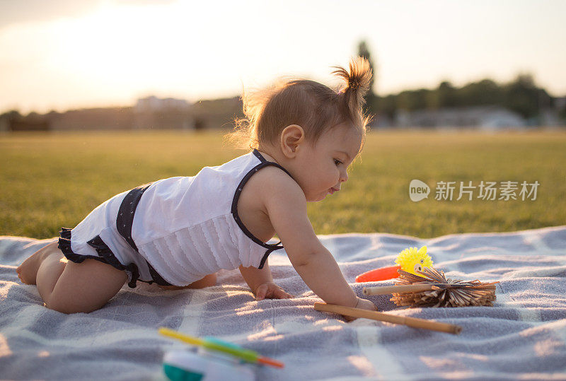 在夏天的一天，小女孩在公园的毯子上爬行