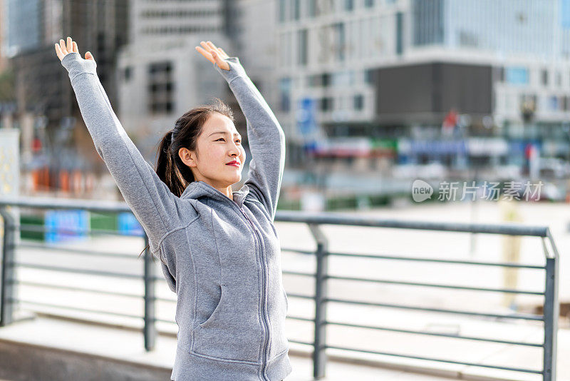 亚洲年轻女子站和伸展后，在城市跑步