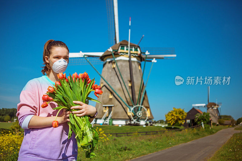 一个荷兰少女戴着面具在传统的风车前