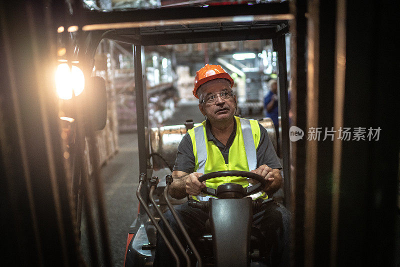 高级男工人在仓库驾驶叉车