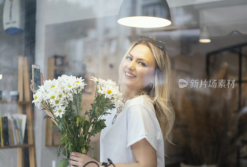 年轻美丽的女人摆姿势与雏菊花在她的家