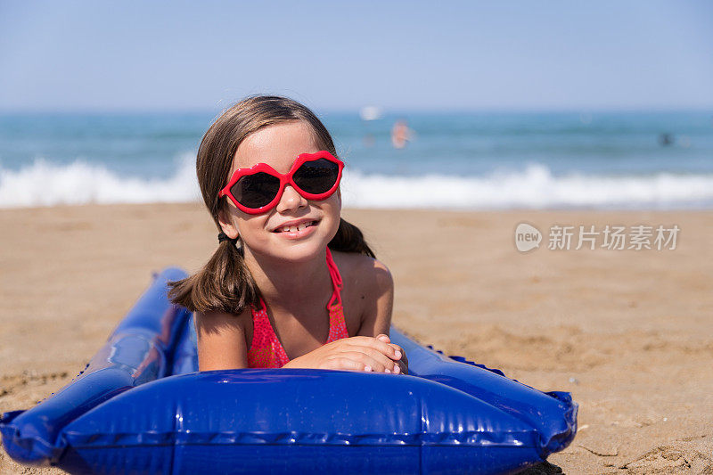 美丽的女孩，带着治愈眼镜躺在沙滩床垫上