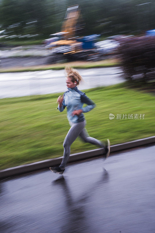 美丽的年轻女子在雨天训练跑步。