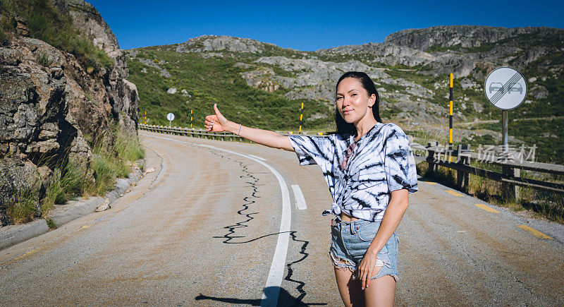 年轻女子搭便车到户外的山区旅行