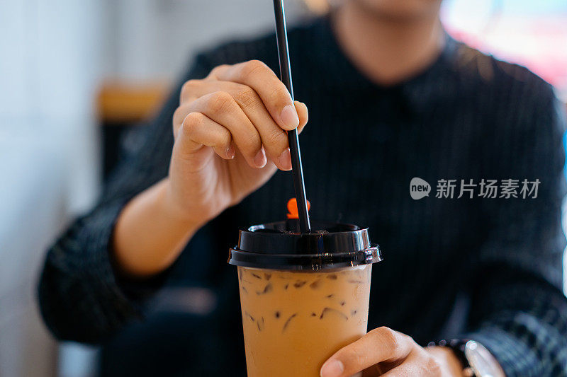 年轻的亚洲妇女把饮料放进她的奶茶饮料