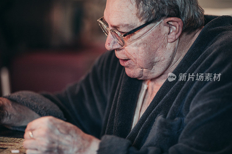 一位老人正坐在餐桌前服药，这是他的日常工作。