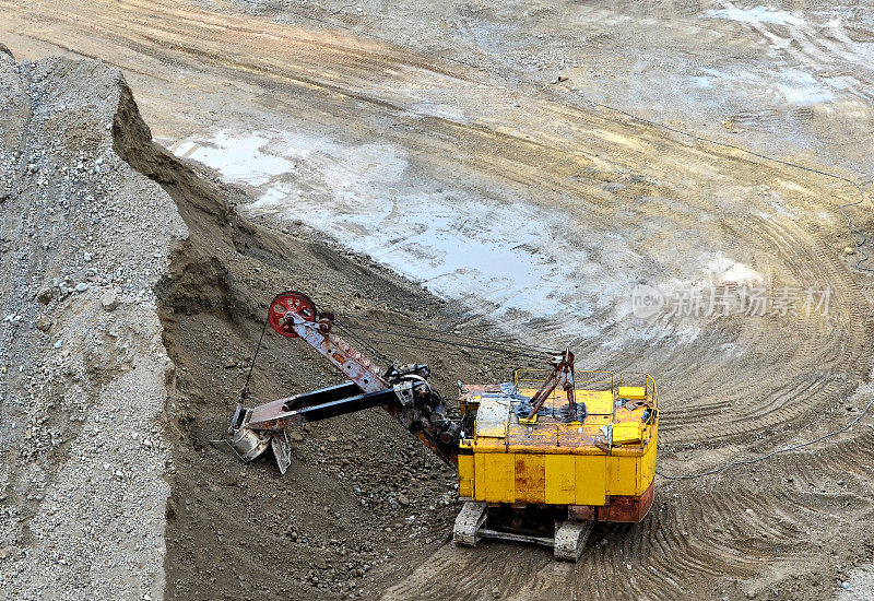 采石场的挖掘机用电铲装载采矿卡车中的岩石。