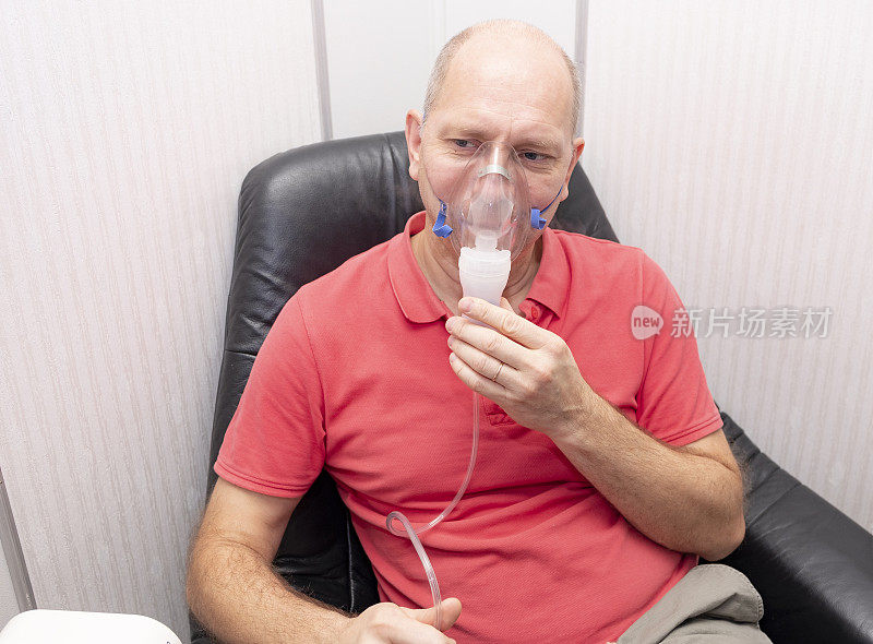 一个40到50岁的白人男性，用喷雾器吸入。