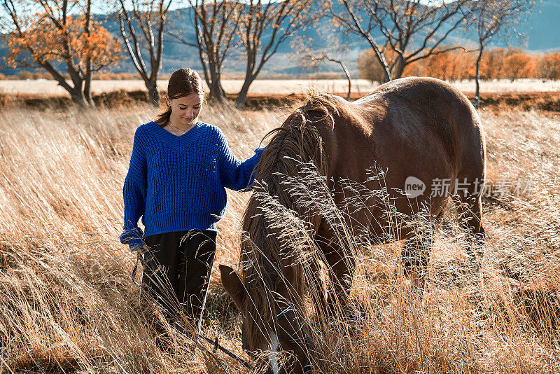 十几岁的女孩穿着休闲装和一匹马散步