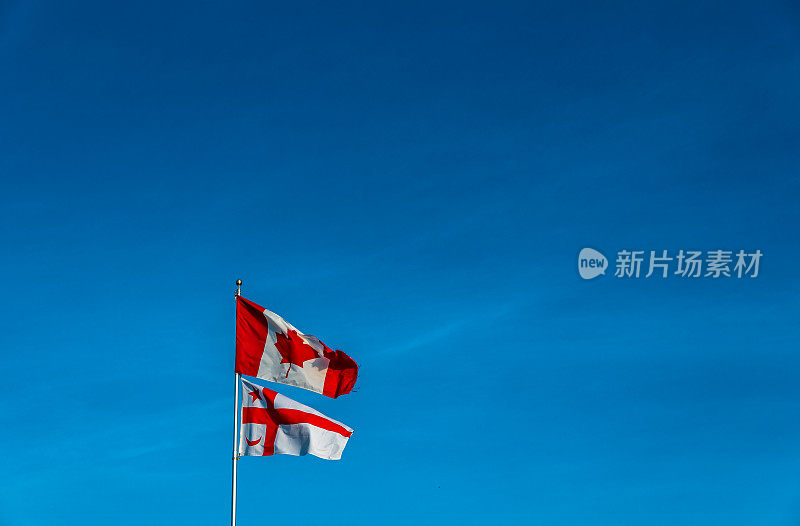 米克玛州国旗飘扬在旗杆上，加拿大国旗在蓝天下飘扬