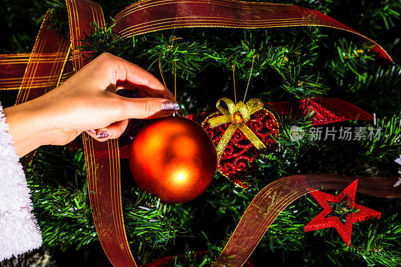 装饰圣诞树，手把圣诞装饰品放在冷杉树枝上。圣诞挂饰。