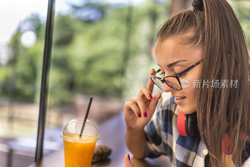 一个年轻漂亮的女人在咖啡店喝果汁。