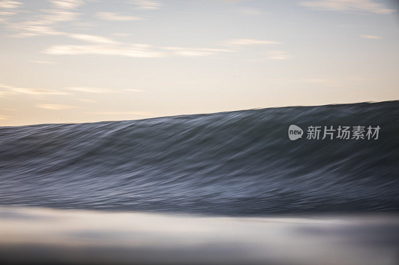 在柔和的桃色天空的映衬下，海浪在海洋中形成