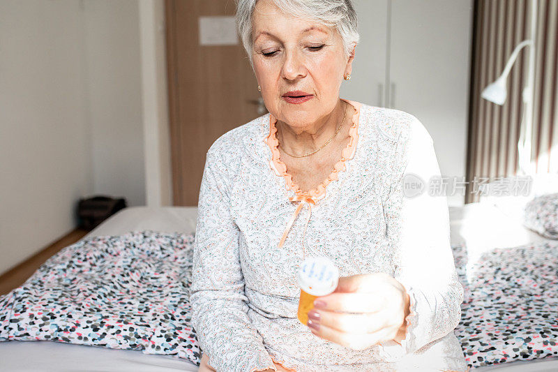 老女人在卧室里，拿着一个药瓶