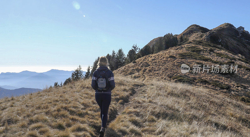 女性徒步旅行者沿着阳光明媚的山脊行走