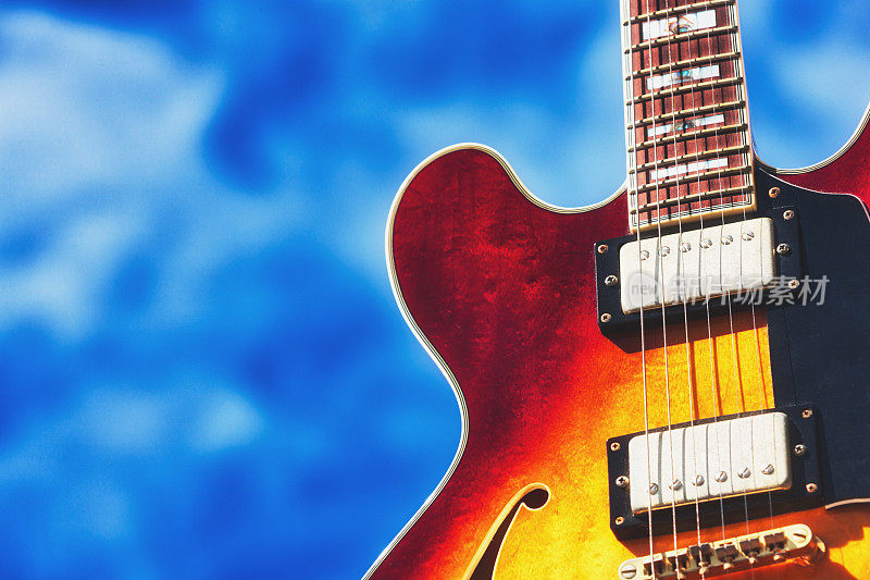 色彩鲜艳的半声电吉他，映衬着微微多云的天空