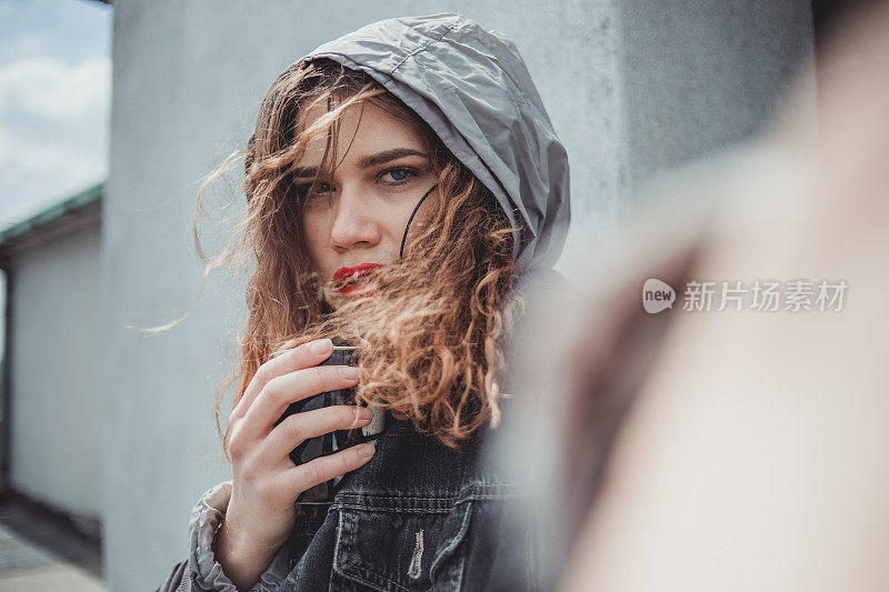 一个美丽的女孩，风的头发在建筑的屋顶享受自由和孤独。