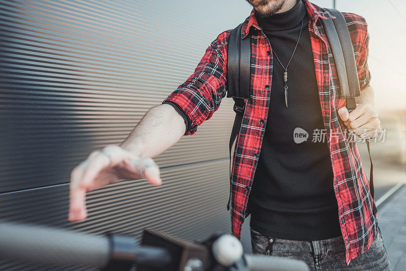 技术、生态的移动性概念。一个赶时髦的年轻人骑着电动滑板车，双手握住滑板车的把手。