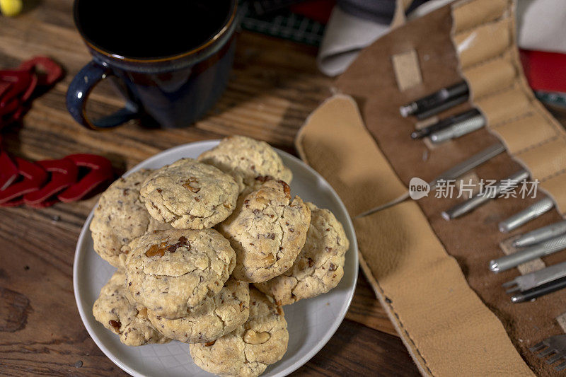 咖啡，胡桃饼干和工作工具放在皮革工匠的木桌上