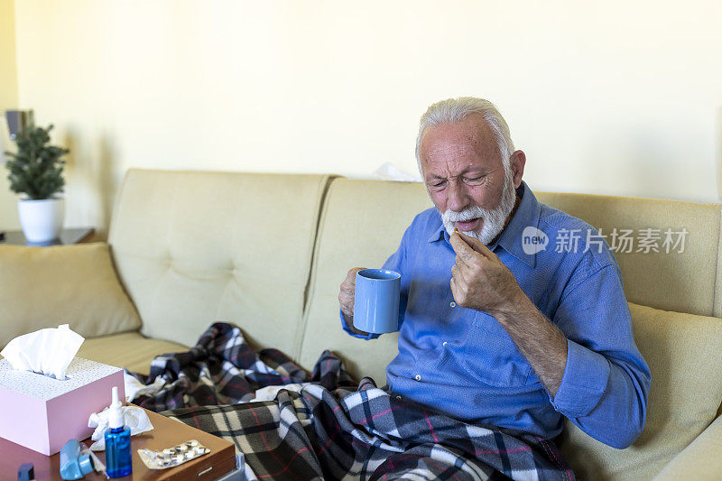 一名患季节性流感的男子躺在床上，喝着热茶和药片恢复健康。