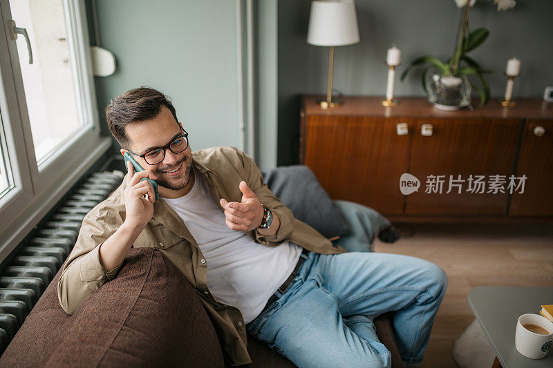 一个英俊的年轻白人男子在家里使用智能手机的高角度视图