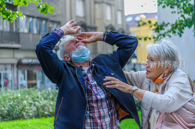 一位有眼病的老人在细心的妻子的帮助下滴眼药水。